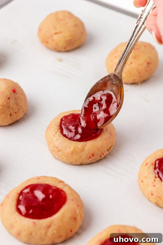 thumbprint cookies being filled with strawberry jam before baking