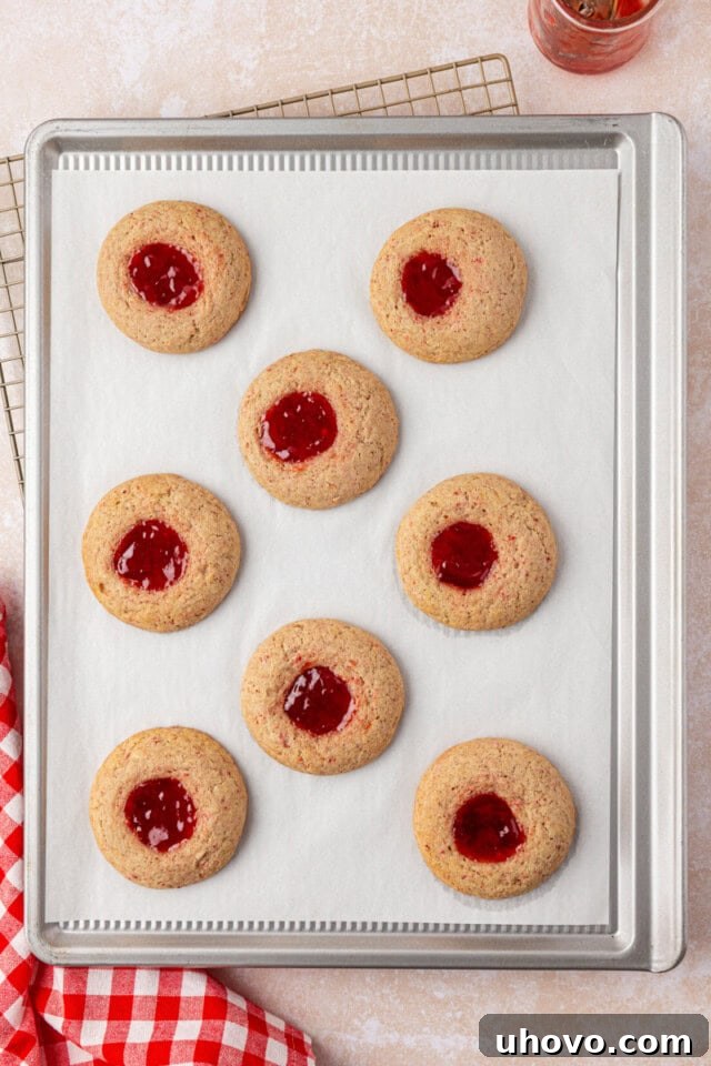 overhead view of freshly baked strawberry shortcake cookies on a lined baking sheet