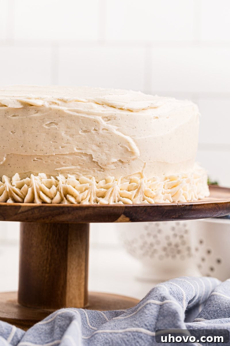 vanilla layer cake frosted with vanilla buttercream on a wooden cake stand