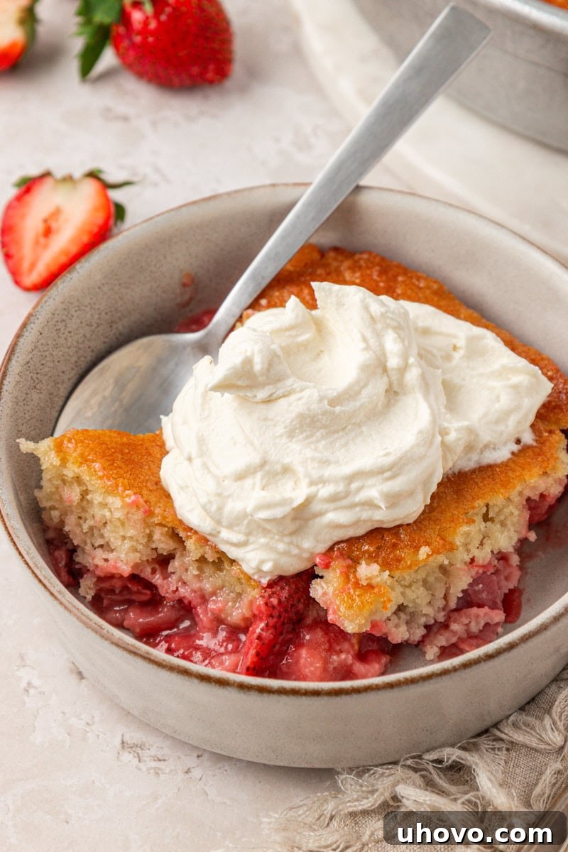 a big dollop of mascarpone whipped cream on a serving of a rustic strawberry cake