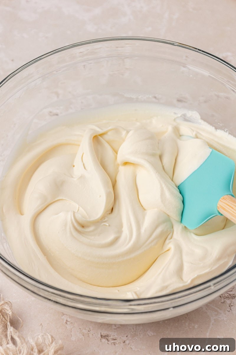 mascarpone whipped cream in a mixing bowl with a rubber spatula