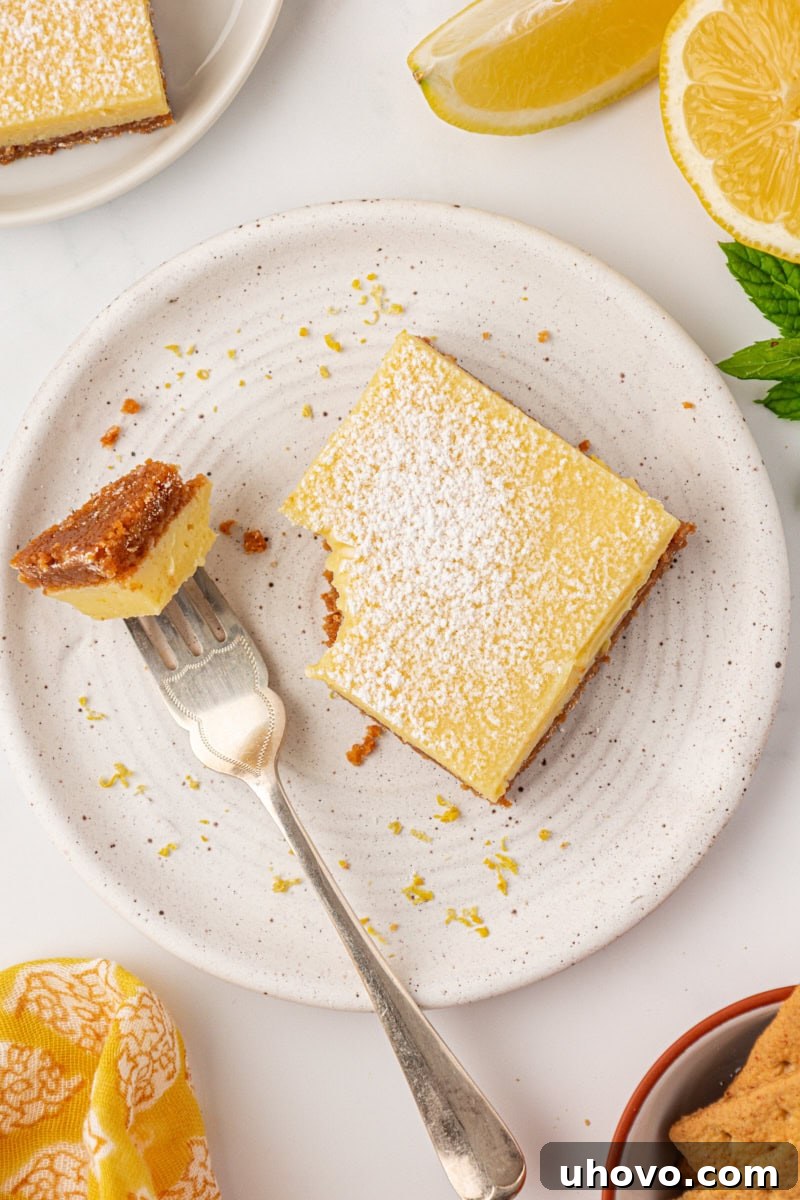 Tangy Lemon Icebox Bars Recipe — Cool, Zesty Dessert with Shortbread Crust 9 a lemon icebox bar on a plate with a bite on a fork