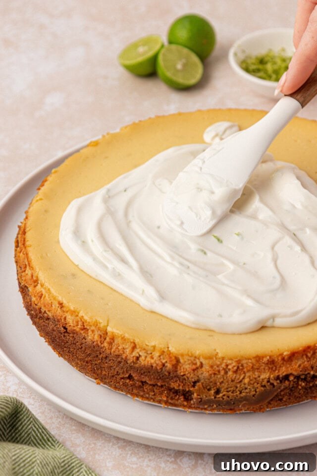 Creamy Key Lime Cheesecake Recipe: Zesty No-Bake Dessert 7 sour cream topping being spread over chilled Key lime cheesecake