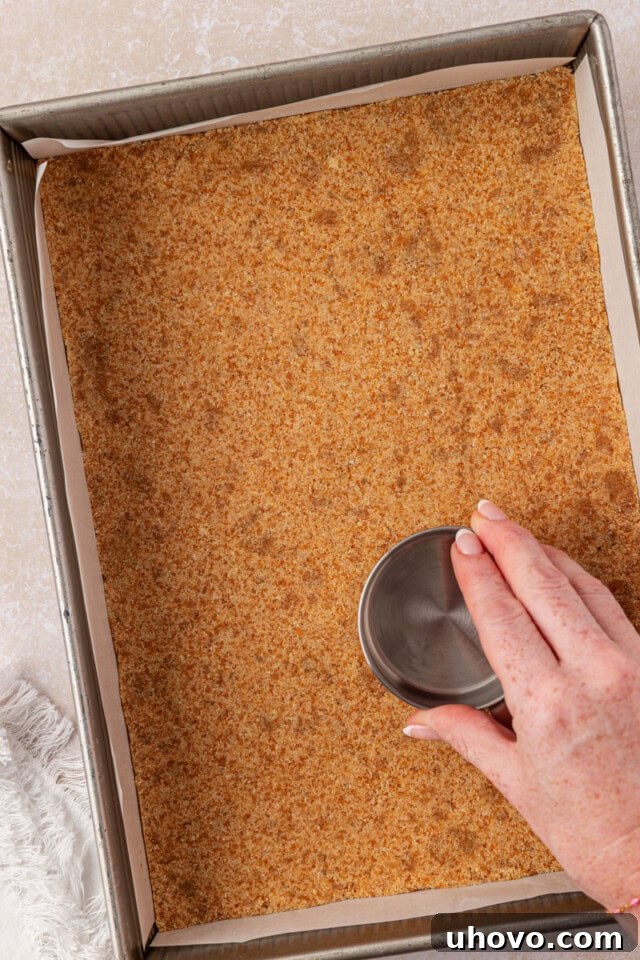Creamy Banana Pudding Cheesecake Bars 4 vanilla wafer crust mixture being pressed into a baking pan