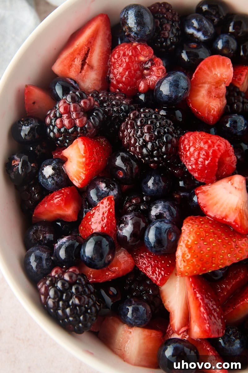 Macerated Berries Recipe: Sweetened Berry Topping for Desserts 2 close up overhead view of macerated berries, including strawberries, blueberries, raspberries, and blackberries