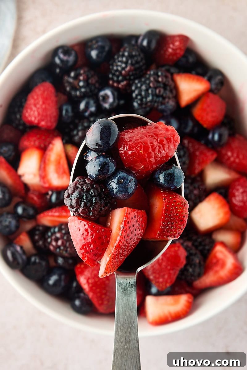 Macerated Berries Recipe: Sweetened Berry Topping for Desserts 7 macerated berries in a serving spoon held over more berries in a bowl