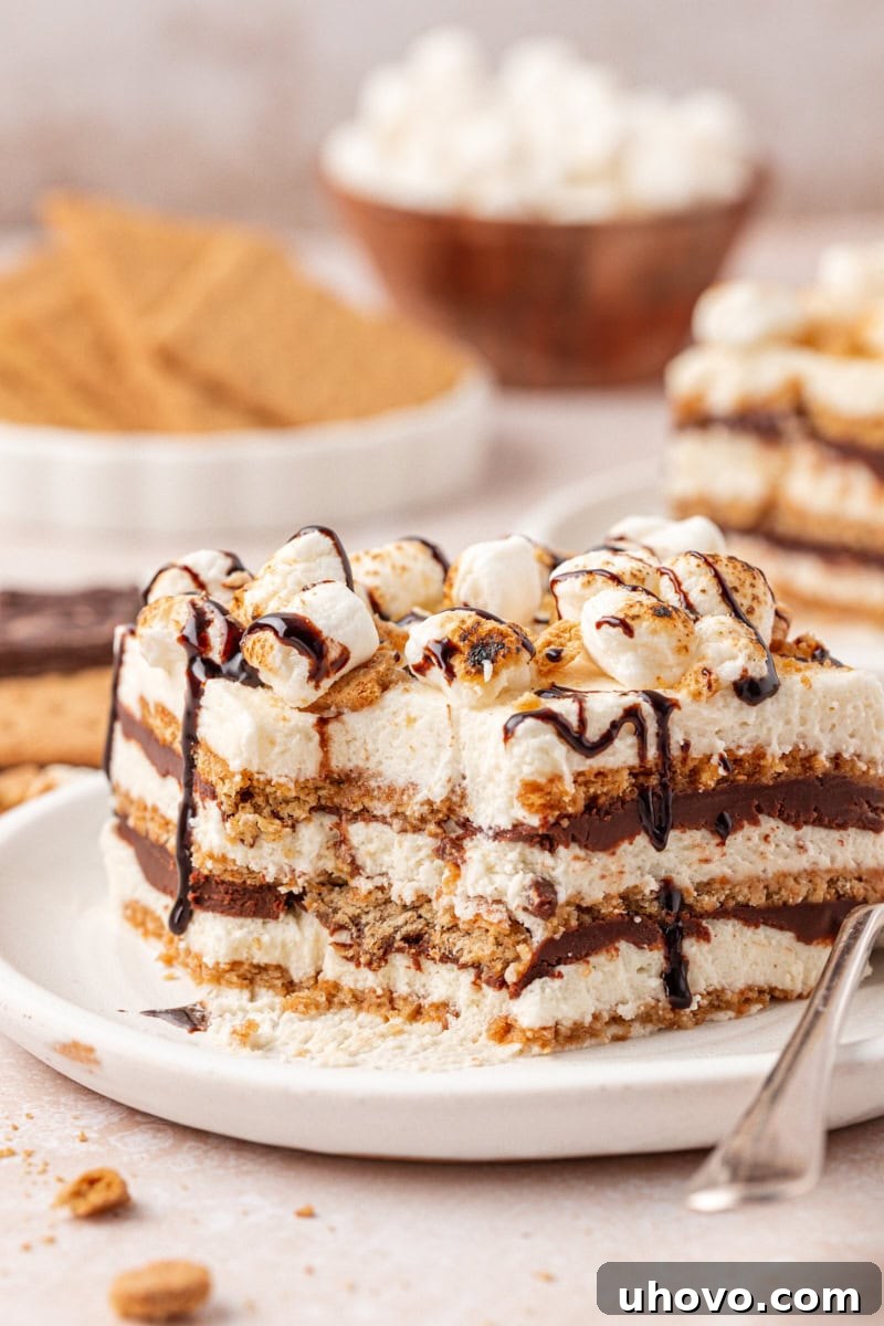 No-Bake S'mores Icebox Cake 11 slice of s'mores icebox cake with layers of graham crackers, marshmallow filling, and chocolate ganache