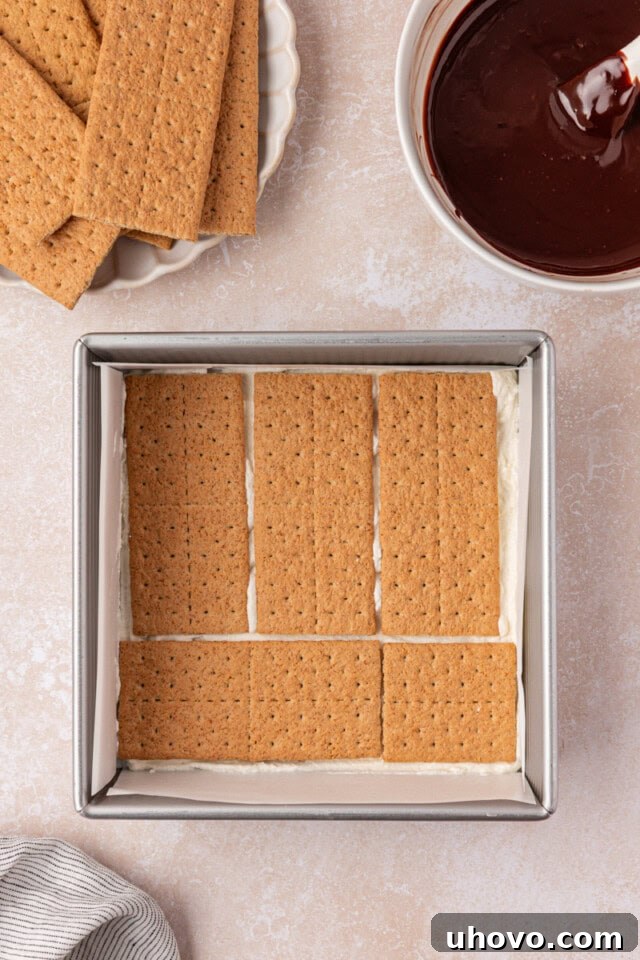 No-Bake S'mores Icebox Cake 4 graham crackers arranged in a single layer over a thin layer of marshmallow filling in a square pan