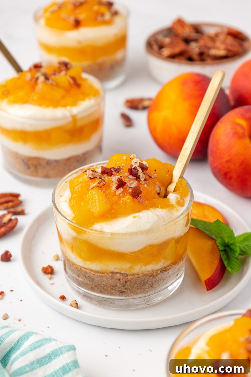 a no-bake peach cheesecake jar with nutty graham cracker crust, fluffy cheesecake filling, and fresh peach compote