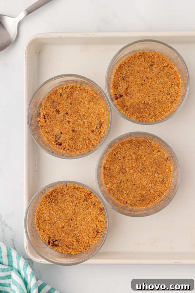 overhead view of graham cracker crust mixture divided between four dessert jars