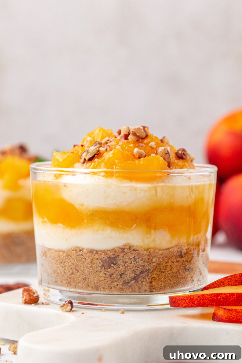 close-up of a peach cheesecake jar with layers of cookie crust, cheesecake filling, and peach compote