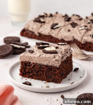 Decadent Oreo Sheet Cake with Creamy Oreo Frosting 13 a slice of chocolate Oreo sheet cake on a white plate with the remaining cake in the background