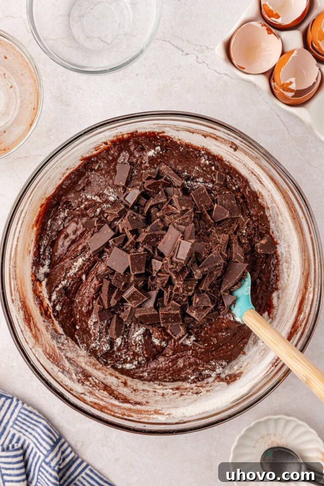 chopped chocolate added to brownie batter in a mixing bowl