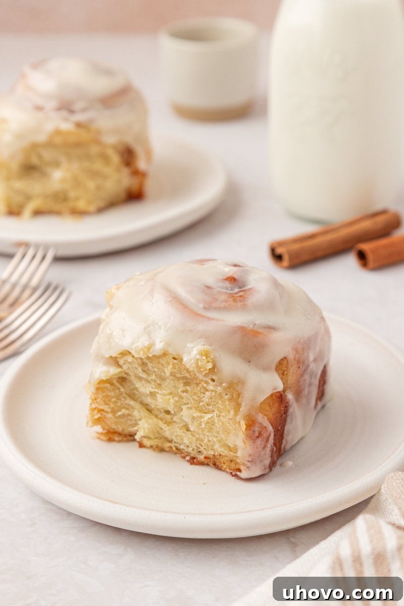 Overnight Cinnamon Roll Recipe for Fluffy Morning Pastry 12 a cinnamon roll topped with cream cheese frosting and served on a white plate