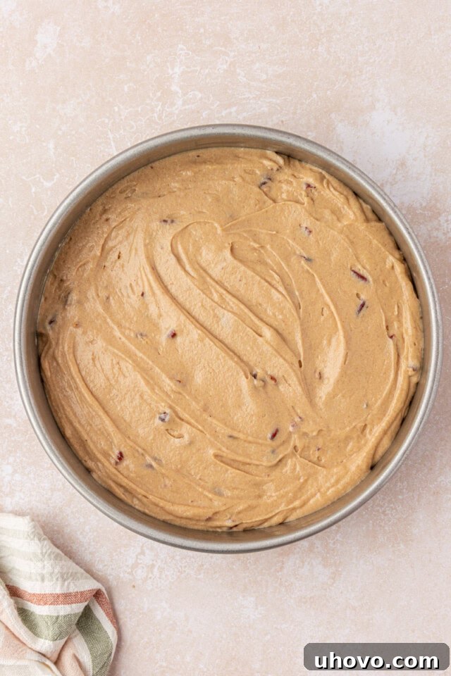 maple cake batter spread in a round cake pan before going into the oven