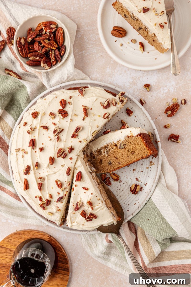 overhead view of a partially sliced single layer maple cake topped with maple frosting and toasted pecans