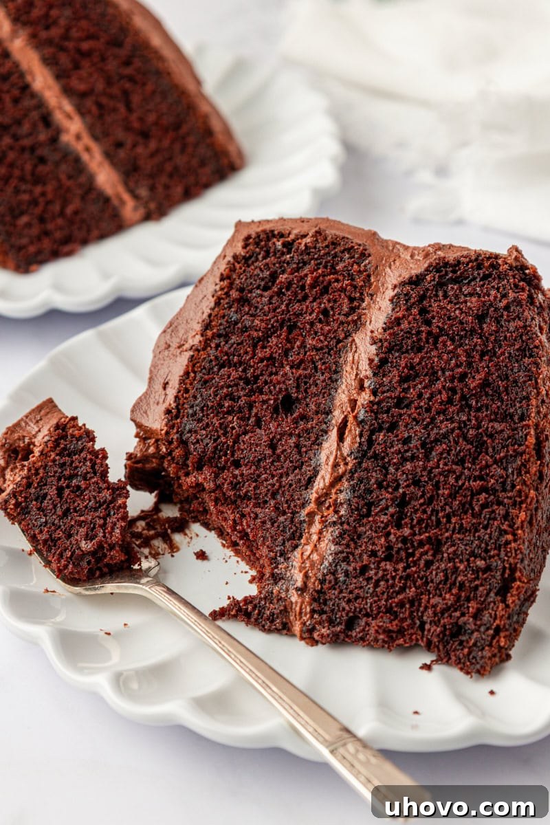 close up of a slice of devil's food cake on a plate with a bite on a fork