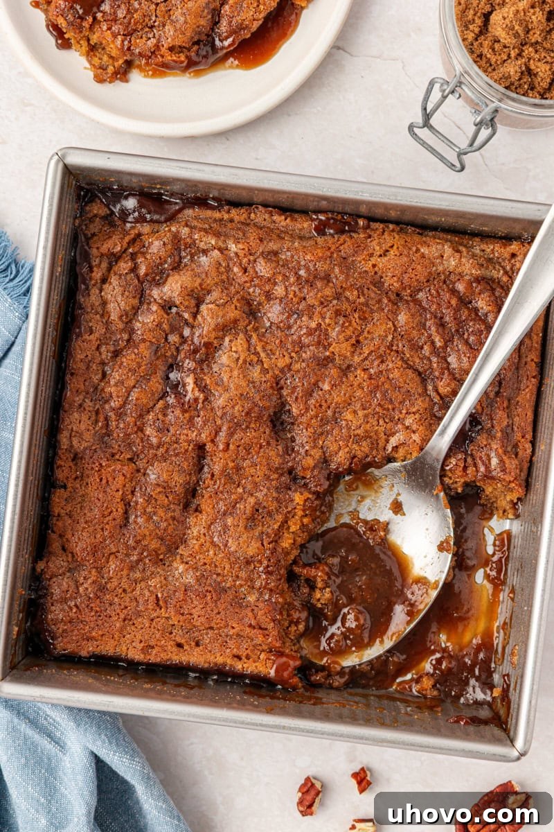 overhead view of butterscotch pudding cake in a square baking pan with a scoop removed