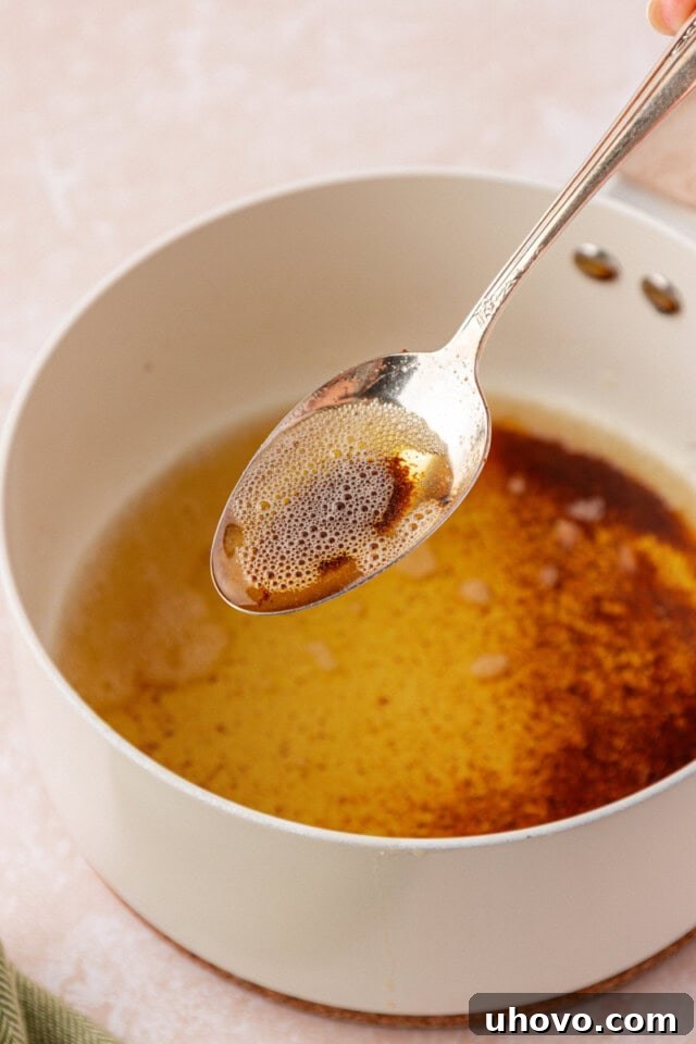 a spoonful of browned butter held over a saucepan