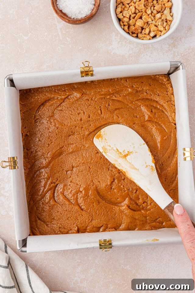 peanut butter blondies batter being spread in a square baking pan