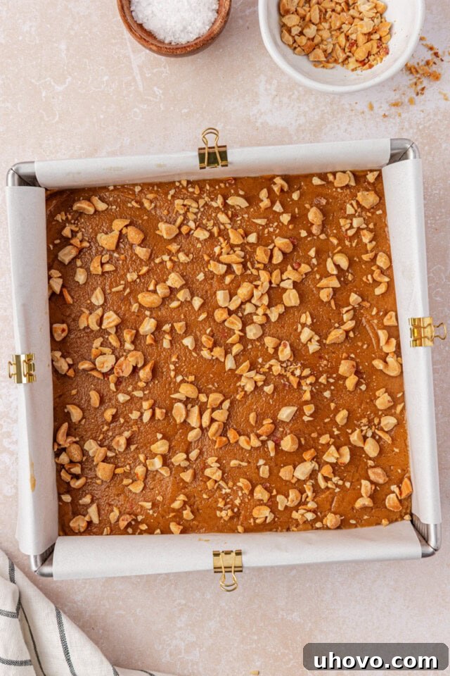 peanut butter blondie batter topped with chopped peanuts before baking